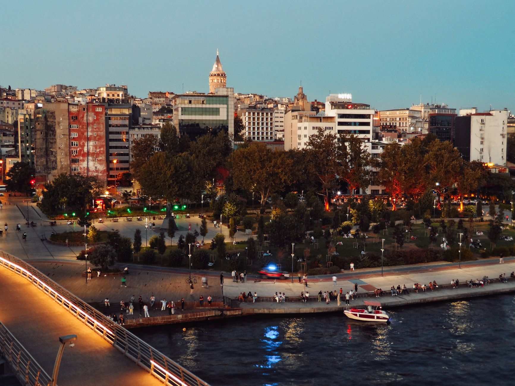 Scenic view of Istanbul's skyline featuring Galata Tower and bustling park at twilight along the waterfront. — Basic facts re
