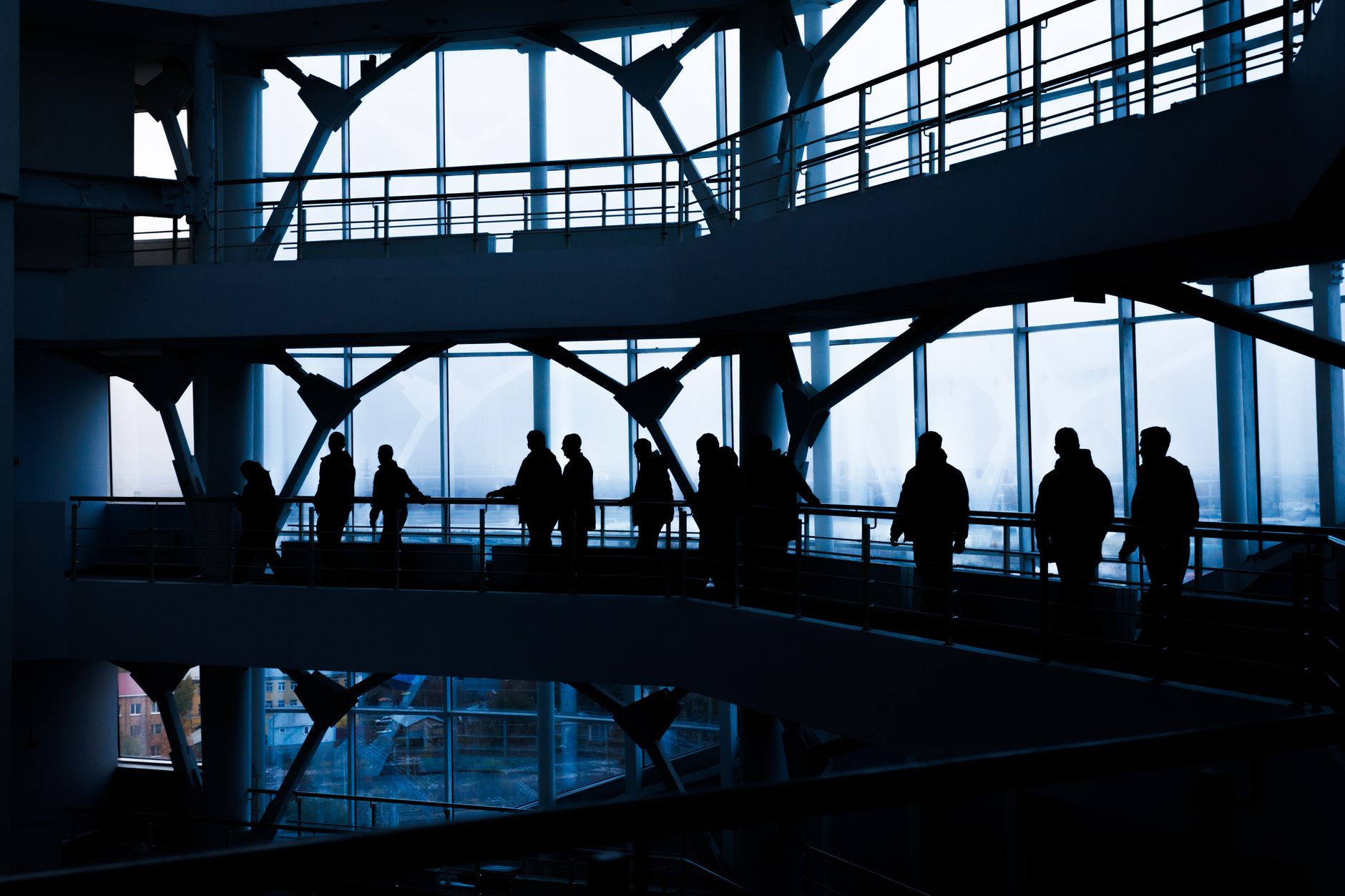 Silhouettes of people walking in a modern architectural building with large windows. — Boosting testosterone production with