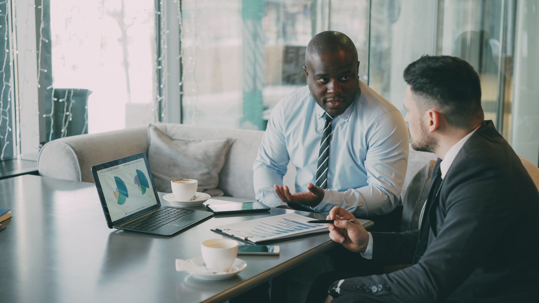Two business professionals engaged in discussion over laptops and documents. — Great Tips For Finding New Clients Through Aff