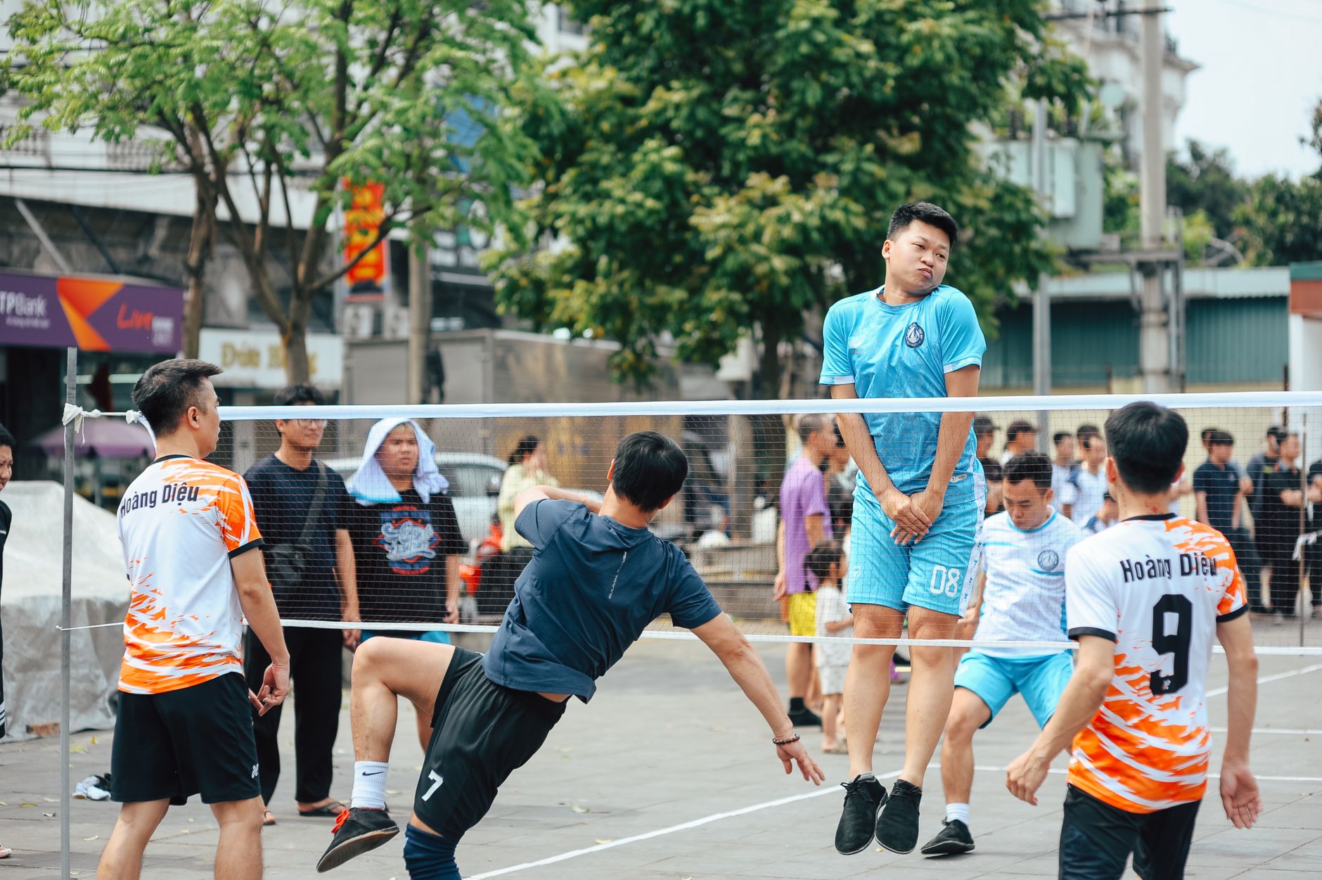 Dynamic foot volleyball game with six adults actively playing in a lively outdoor park scene. — How does the sports community