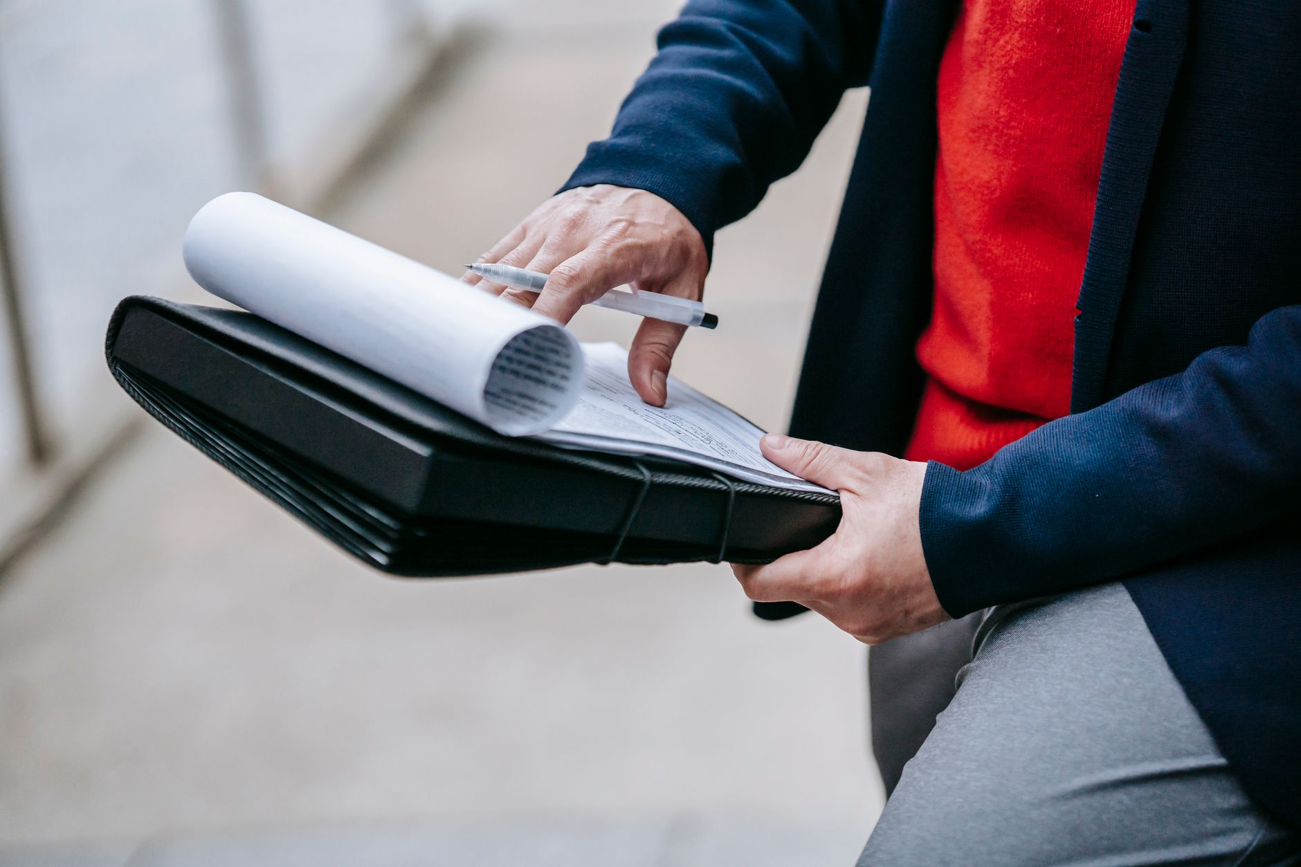 Close-up of a professional person reviewing documents outdoors. Engaged in work with focus on writing materials. — How Instal