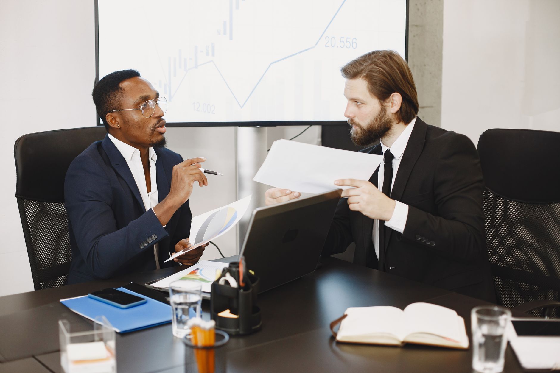 Two business professionals engaged in a planning meeting, discussing documents in a modern office setting. — Information on t