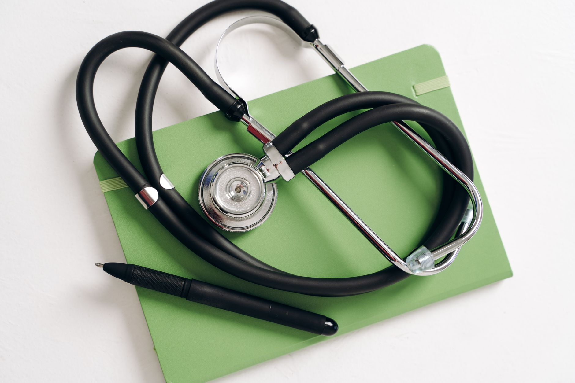 Top view of a stethoscope and pen on a green notepad, ideal for medical and educational themes. — Medical Marijuana Doctors W