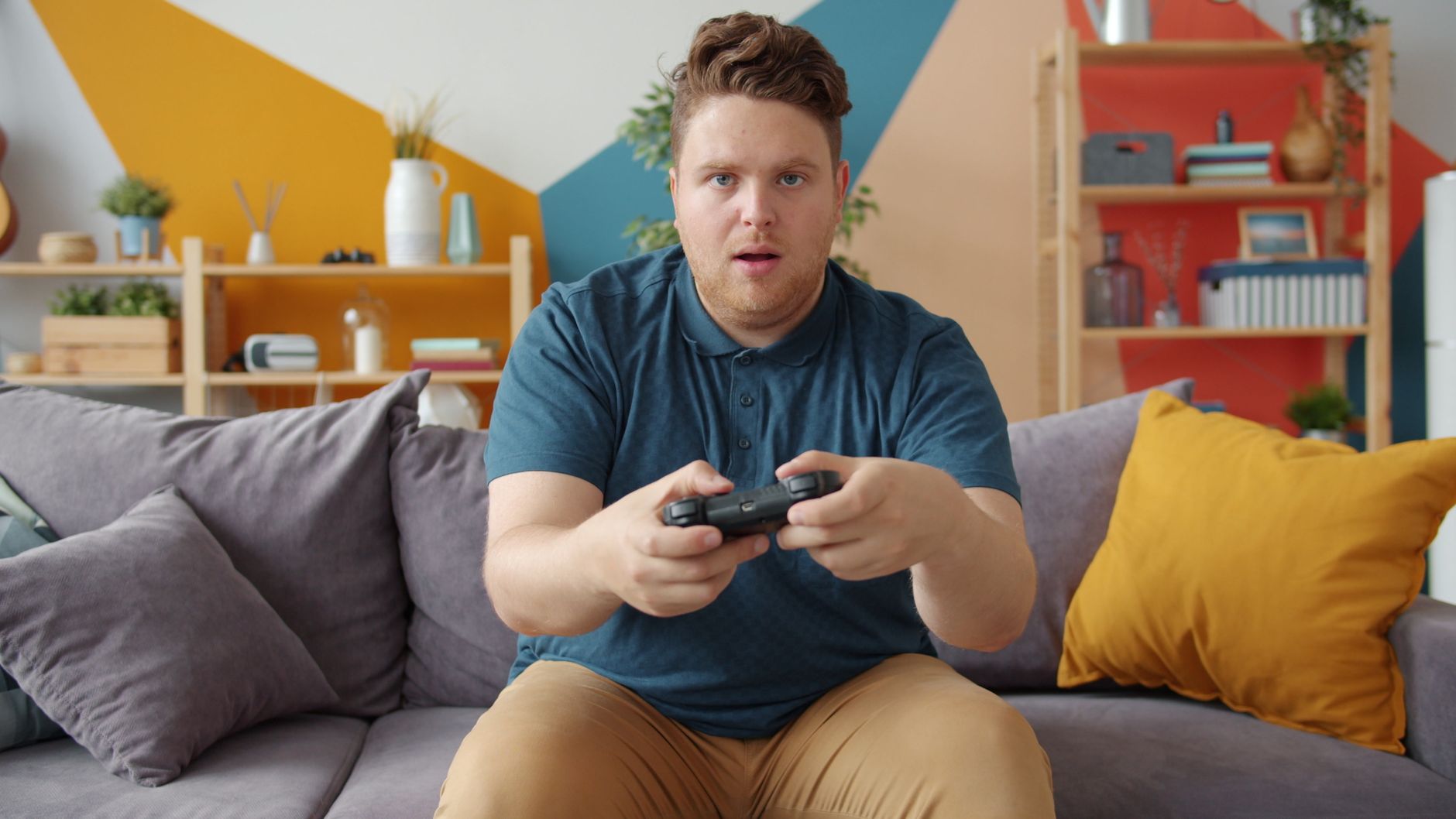A young man intensely playing video games in a modern living room setting. — Start Your Gaming Fun In No Time With Online Cas