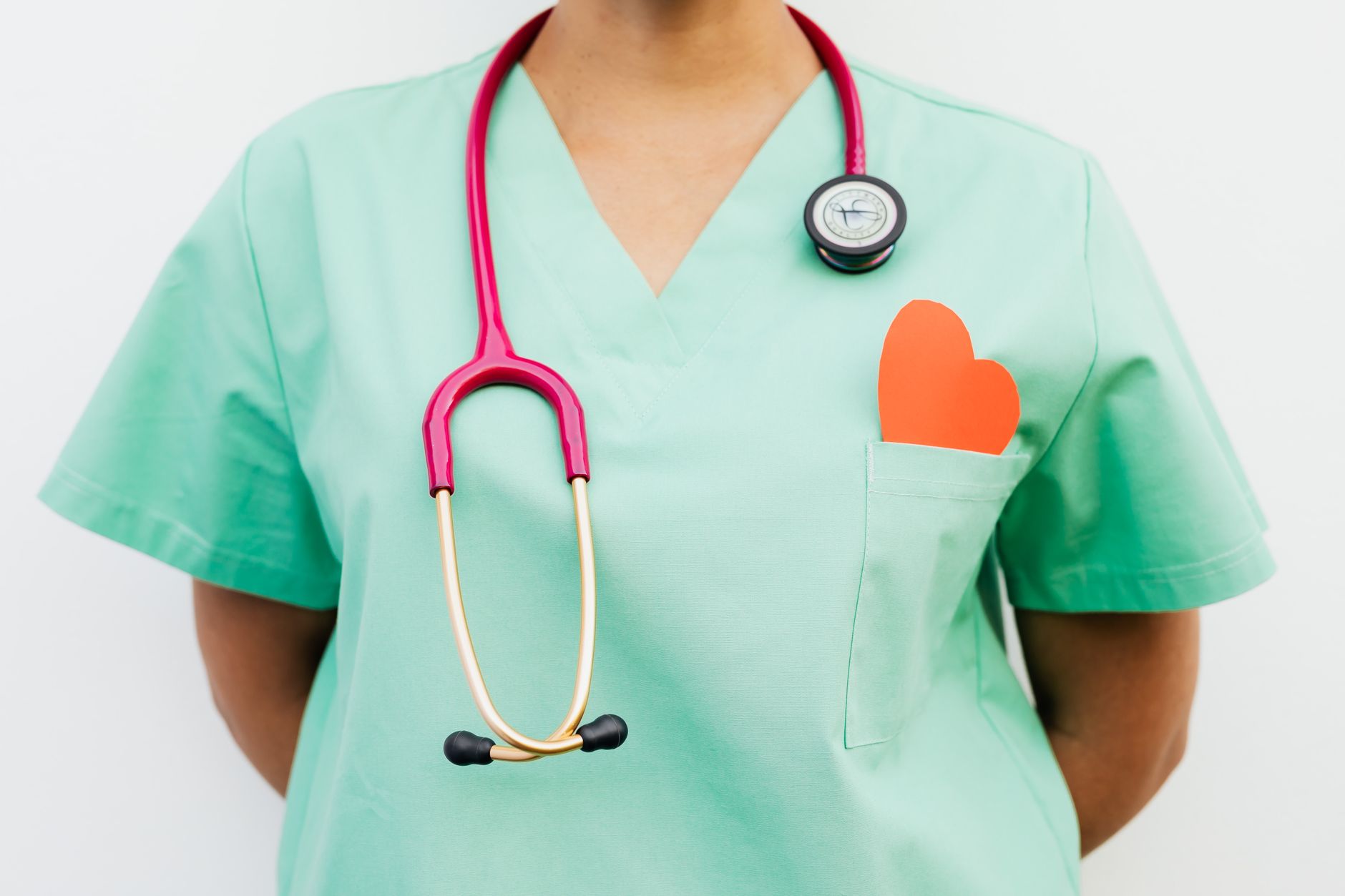 Close-up of a medical professional with a stethoscope and a paper heart cutout on a green uniform pocket. — Supplements for M