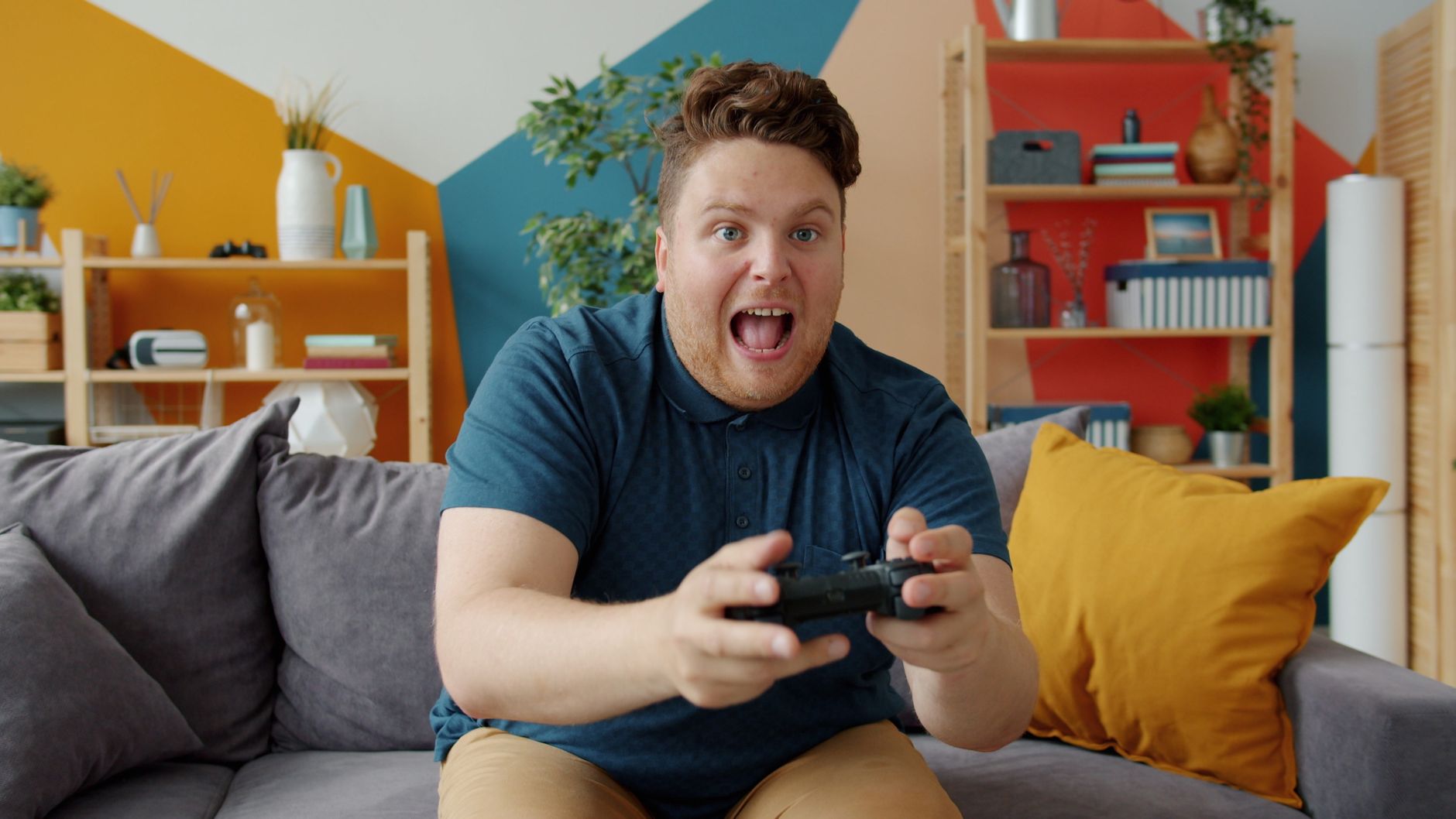 Enthusiastic adult male playing video game on console in colorful, modern living room. — Unknown advantages that everyone can