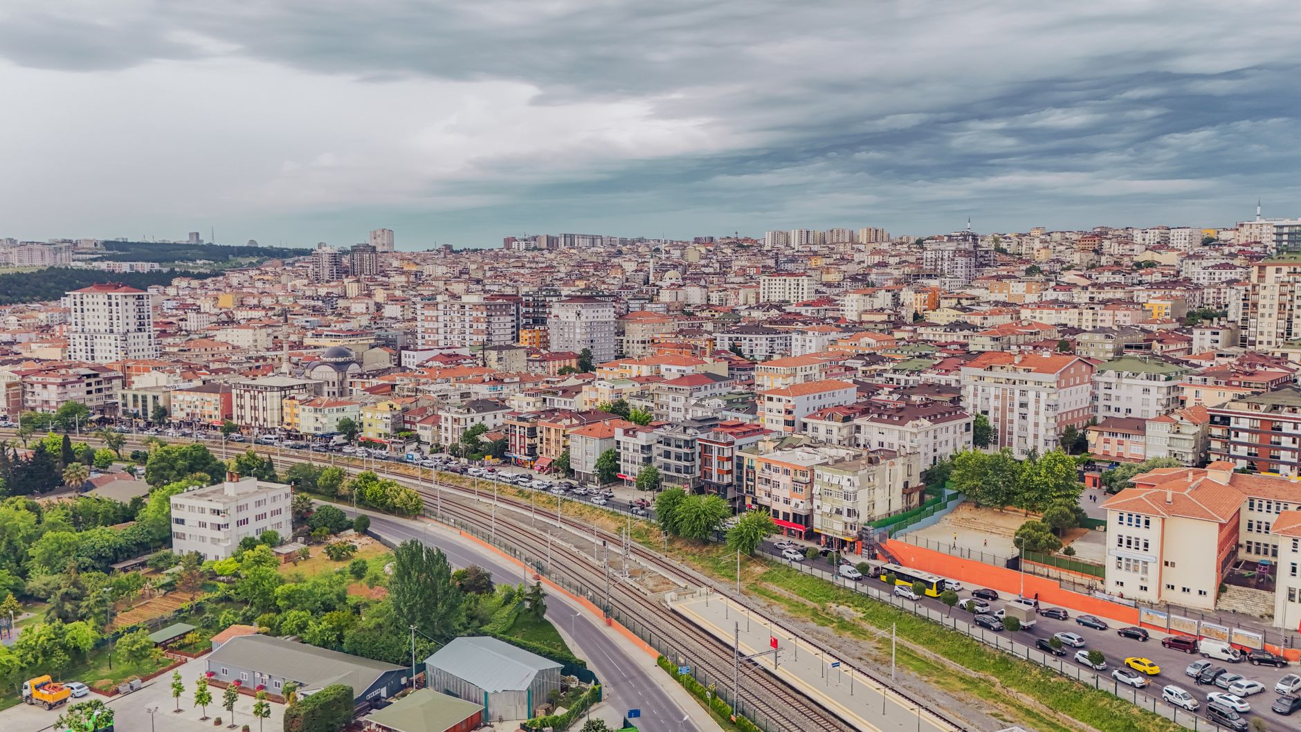 Aerial view of dense urban architecture with roads and greenery under cloudy skies. — Why Should You Develop a Photo Book?